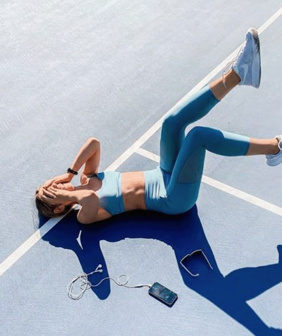 Woman lying on tennis court in athletic gear.